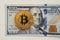 Bitcoin on 100 dollar bill background. gold coin of bitcoin on a hundred dollar bill