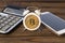 Bitcoin, alarm clock, calculator, smartphone on a wooden background.