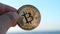 Bitcoin coin close up. Person holding Bitcoin coin on background sea shining sun