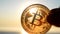 Bitcoin coin close up. Person holding Bitcoin coin on background sea shining sun