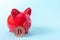 Bitcoin coin and red piggy bank on a blue background, close-up, copy space. Cryptocurrency saving concept