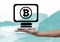 Bitcoin computer icon and hand holding phone