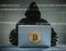 Bitcoin gold coin and anonymous hacker sittign with laptop.