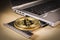 Bitcoin golden coin over a laptop`s CD drive