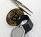 Bitcoin with magnifying glass and tweezers