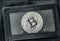 Bitcoin metal coin laying on black leather wallet.