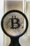 Bitcoin metal coin under glass prism and magnifying glass