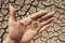 BITCOIN OVER DRY LAND IN HAND SYMBOLIZING GLOBAL WARMING AND CRYPTO MINING