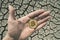 BITCOIN OVER DRY LAND IN HAND SYMBOLIZING GLOBAL WARMING AND CRYPTO MINING