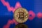 Bitcoin physical coin symbol with downtrend price graph background