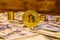 Bitcoin, stacks of the coins and one hundred dollar bills on wooden table