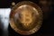 Bitcoin Symbol on a Round Golden Emblem Surrounded by Zeroes and Ones