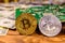 Bitcoins, circuit board and one hundred dollar bills on a wooden