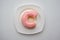 Bite donut ring with strawberry flavor glaze frosting on white p