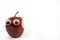 Bitten fake styrofoam red apple with large googly eyes against a white background