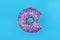 Bitten glazed donut with colorful sprinkles on a blue background