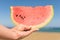 Bitten ripe piece of watermelon in woman hands on the beach in a hot summer day. Concept.