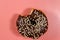 Bitten tasty chocolate donut on pink background. Top view