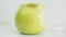Bitten yellow apple fruit on white plate rotates