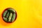 Bitter cucumber on plate on yellow background,called Karela in Hindi,Copy space, top view