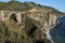 Bixby Creek Arch Bridge surrounded by hills covered in greenery and the sea under the sunlight