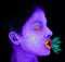 Bizarre beauty. a young woman posing with neon paint on her face.