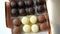 Bizze airy souffle desserts in the form of sweets in the glaze of white, black and milk chocolate. Box of chocolates on