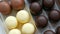 Bizze airy souffle desserts in the form of sweets in the glaze of white, black and milk chocolate. Box of chocolates on