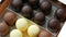 Bizze airy souffle desserts in the form of sweets in the glaze of white, black and milk chocolate. Box of chocolates on