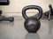 Black, 10 kg kettlebell sitting on hard gym floor with space to