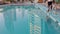 Black African American man cleaning pool. View of Dubai city with high-rise towers reflecting in water of swimming pool