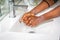 Black African Australian woman washing hands with soap in sink