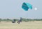 Black African male skydiver making safe landing on grass with op