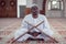 Black African Muslim Man Is Praying In The Mosque with open holy book of Koran