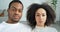 Black afro american couple young family newlyweds sitting on couch looking at camera with serious thick expression wear