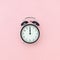 Black alarm clock in center on pink background, closeup. Minimal style Copy space Top view Template for your text, design