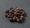 black allspice peppercorns close-up on gray background