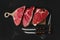 Black angus beef steaks on wooden board: top sirloin, strip steeak and top round roast