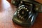 Black antique vintage analog telephone dialing or scrolling phone on wooden table.