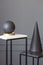 Black, art deco sculptures on metal stands against gray wall wit