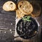 Black Astrakhan Russian salted sturgeon caviar in a can on dark background with wooden spoon and slices of bread. Snacks