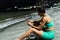 Black athlete in sportswear, using cell phone while sitting on the sand and resting during break in fitness training on the beach