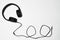 Black audio headphones and cord on white background