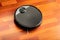 Black automatic vacuum cleaner robot in a house to clean the floor and help in housework. Smart device