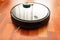 Black automatic vacuum cleaner robot in a house to clean the floor and help in housework. Smart home, internet of things