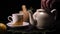 On a black background, a brewed teapot teapot on a tray is a lemon and a grassy saucer, from the kettle a lot of steam comes out