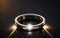 A black background with a light beaming in the middle of the ring and a shiny gold ring on it.