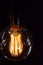 On a black background light bulb Tesla. Place for the text. These Edison style bulbs are beautiful but are high consume electrici