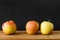 black background three apples wooden table
