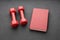 On a black background two red dumbbells and one red book. symbols of knowledge and power